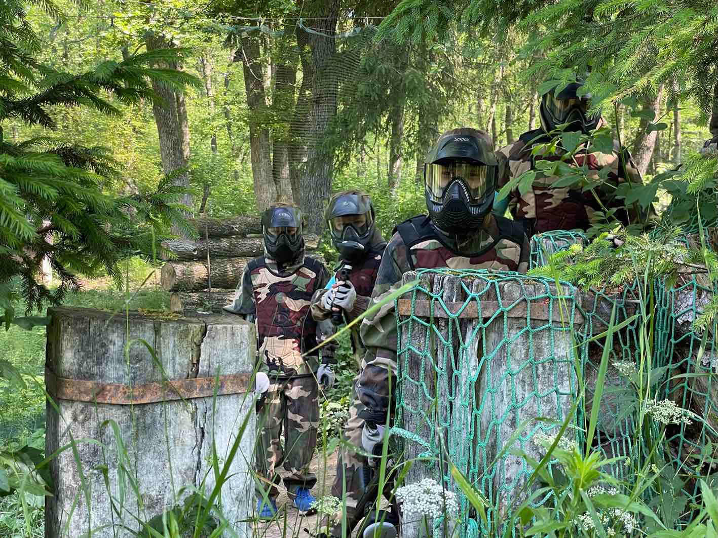 Paintball Park Spyder ekipa 4 fantov, ki se v poligonu skrivajo pred napadalci. oblečeni so v kamuflažno obleko in nosijo zaščitno masko na obrazu